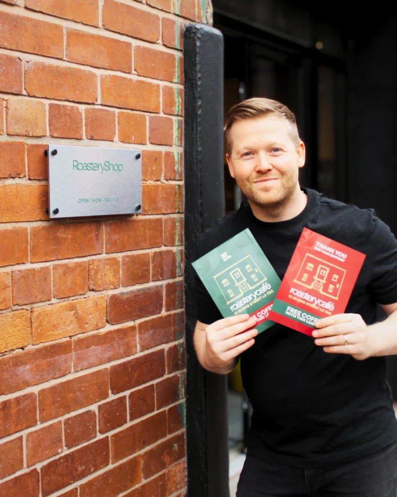 Crosby Coffee Ten Streets Are Giving Away 10,000 Free Coffees - Here's How To Get Yours 2 Co-owner Mark holding leaflets offering free coffee at Crosby Coffees new roastery café