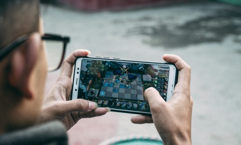 Why Mobile Games Fit Modern Attention Spans 1 A person holding a mobile phone playing a game on it